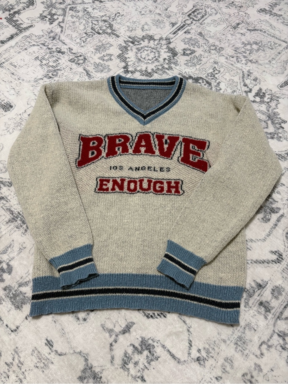 NFINITY Cream V-Neck Sweater with Red Lettering and Blue Trim